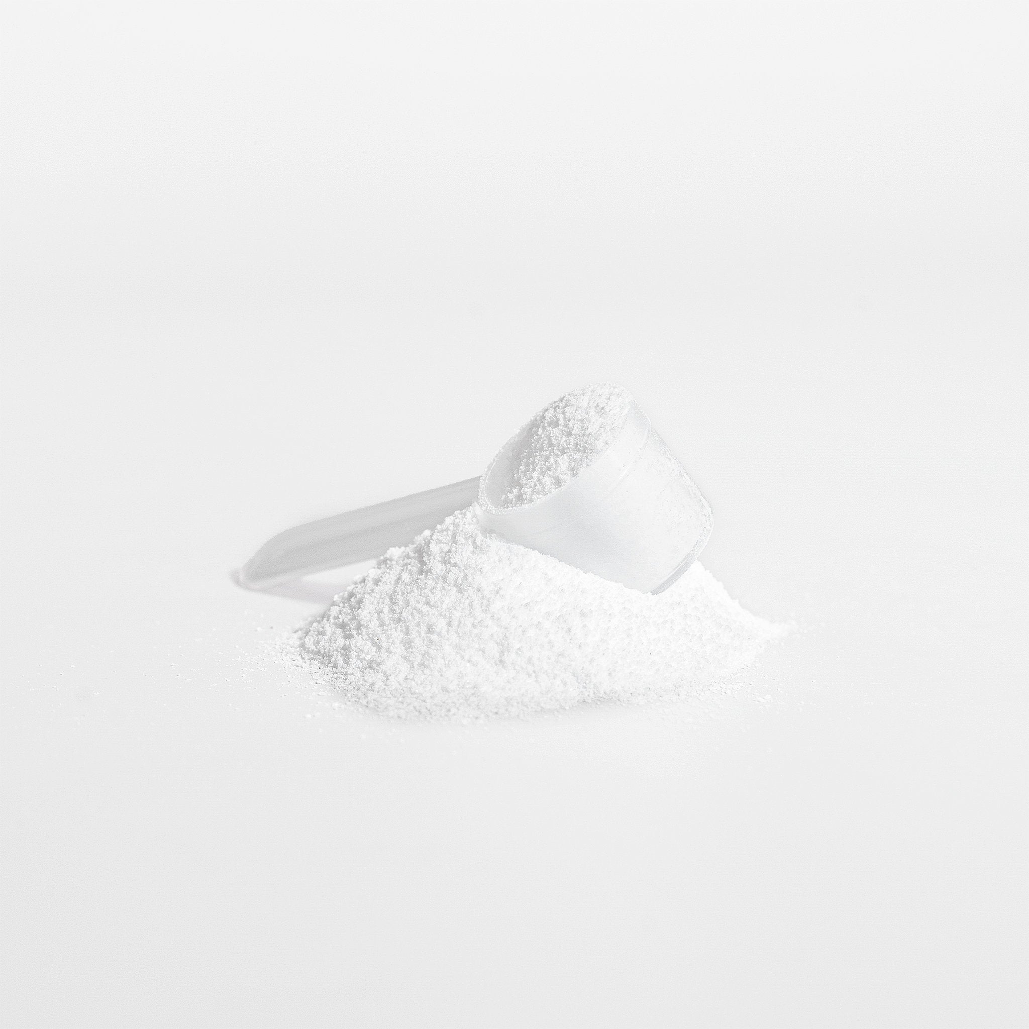 White powder in a measuring spoon on a white background