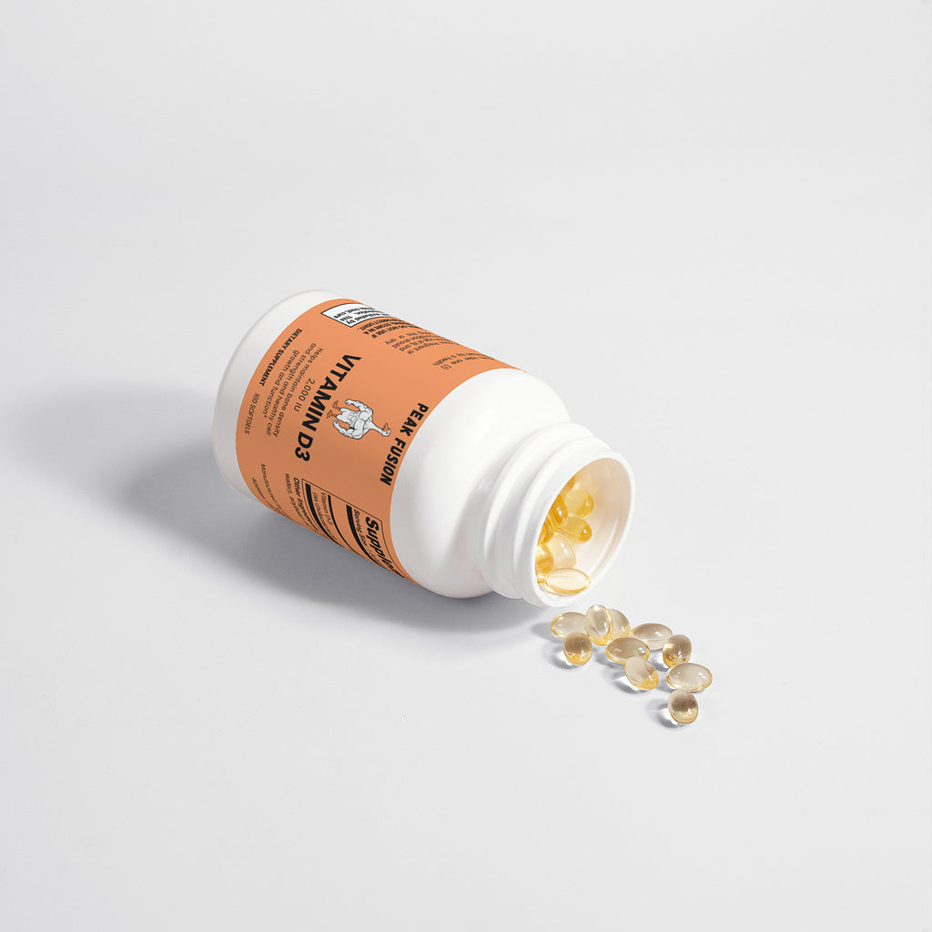 Vitamin supplement bottle with pills spilling out on a light gray background