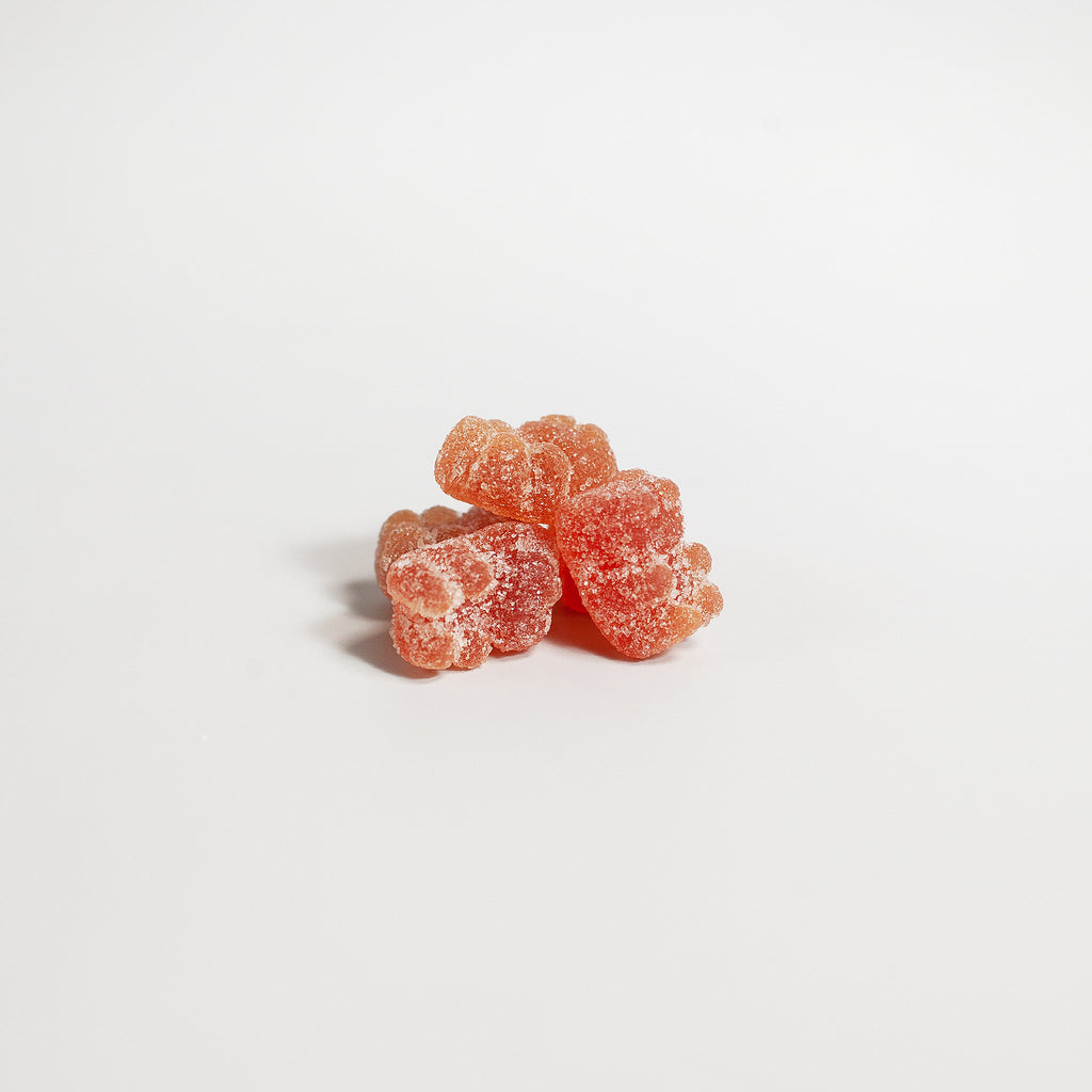 Three pink gummy bears on a light gray background